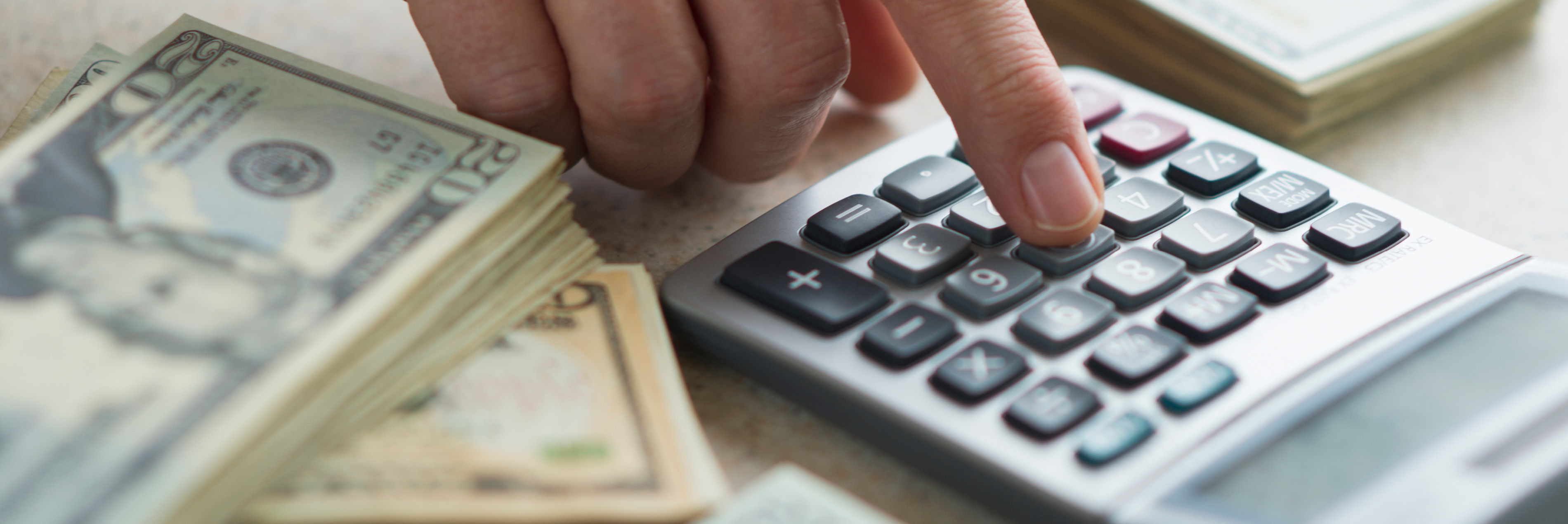 photo of $20 bills and a person on a calculator