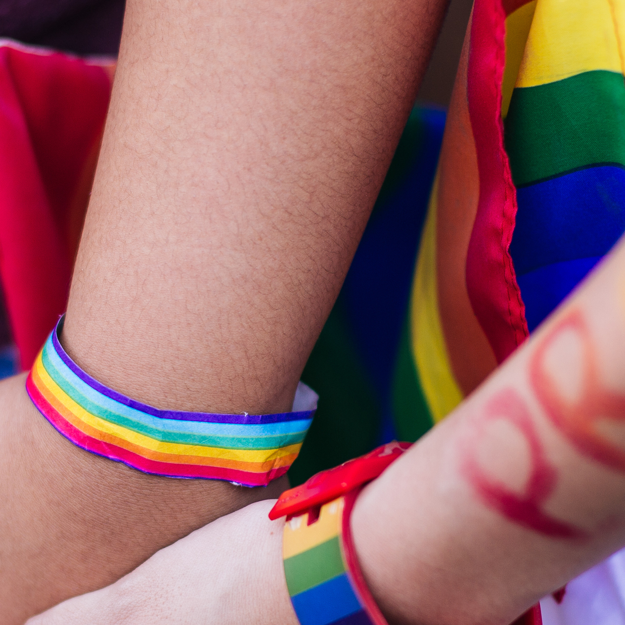 two hands holding each other with pride bracelets